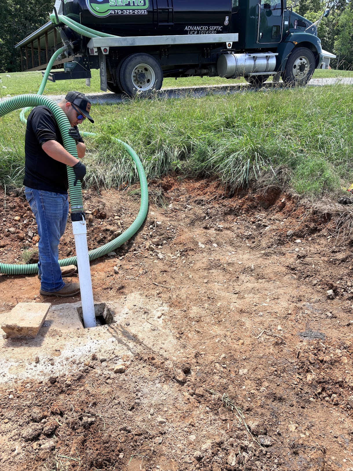 Advanced Septic technician cleaning a septic tank at a Northwest Arkansas property